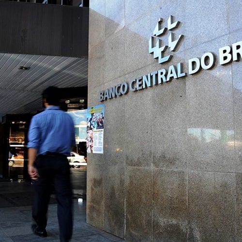 Homem caminhando em frente à sede do Banco Central do Brasil